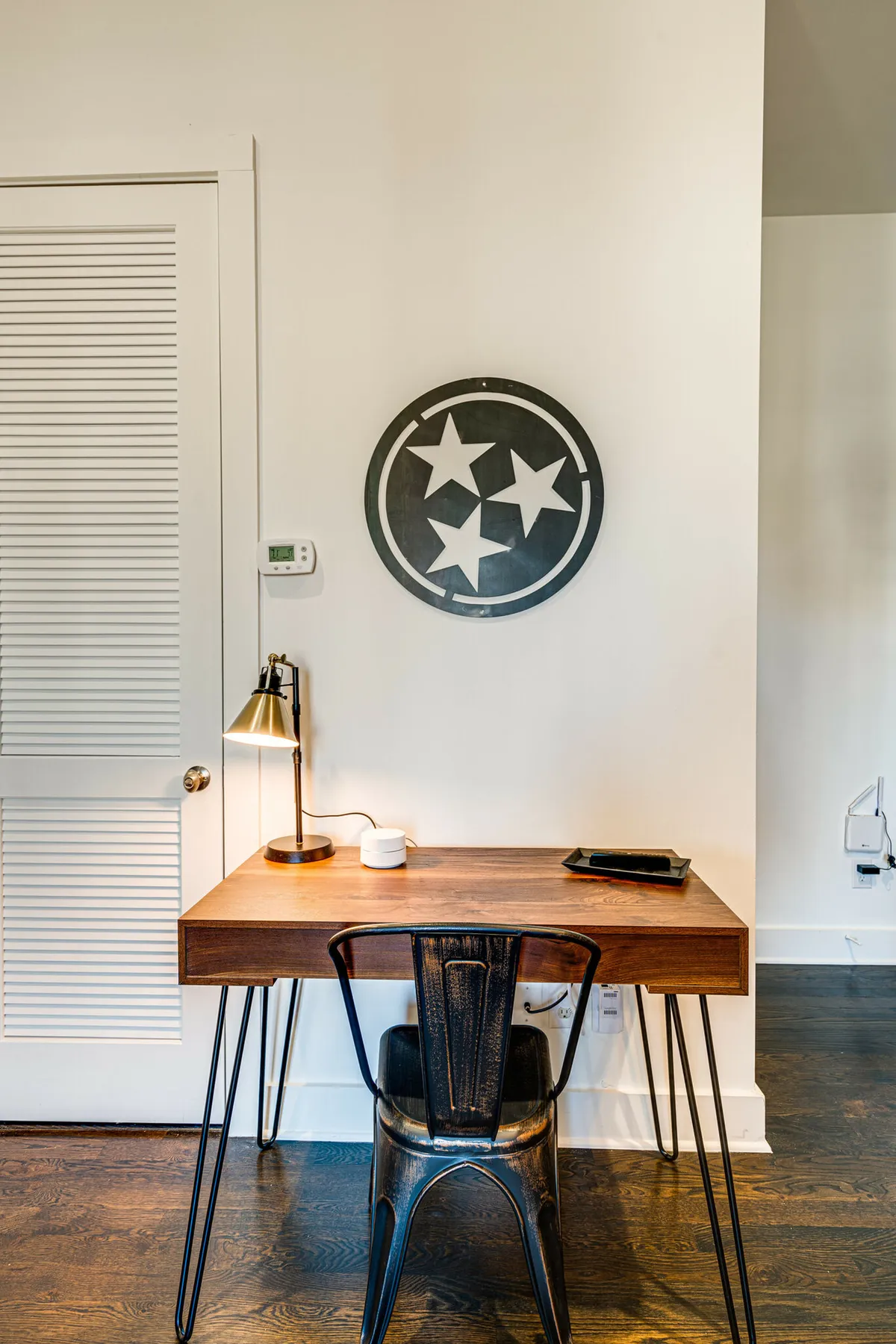 A thoughtfully designed workspace with a sleek desk, chair, lamp, and minimalist wall art. The area feels calm, organized, and conducive to productivity or planning.