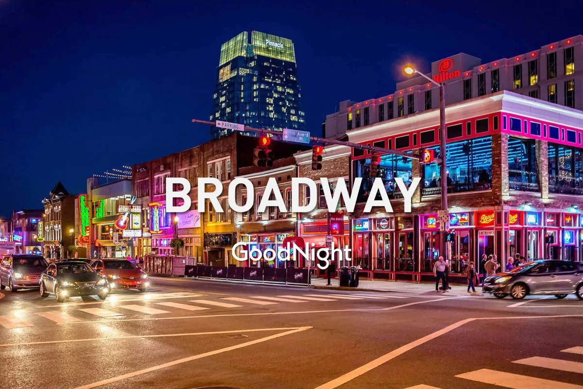 A lively nighttime scene on Broadway, filled with bright neon signs, bustling crowds, and tall buildings, capturing the excitement of Nashville’s world-famous honky-tonks and vibrant nightlife just minutes away from the property.